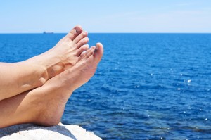 bare feet of a man who is relaxing near the ocean in the summer without hammertoes